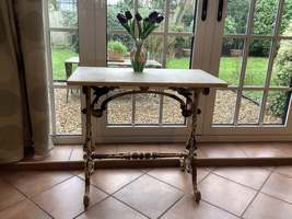 A small cast iron garden console table with marble top